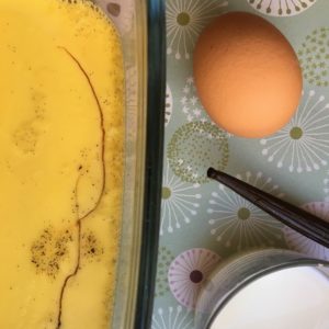 photo d'un plat de crème renversée, d'un oeuf, d'une gousse de vanille et d'une coupe de lait.